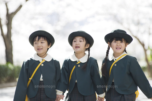 桜並木で手をつないで歩く4人の幼稚園児[10112001401]の写真・イラスト