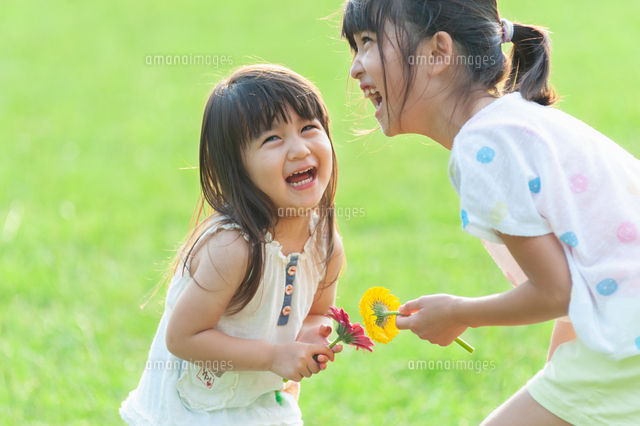 花を持って笑う姉妹 の写真素材 イラスト素材 アマナイメージズ