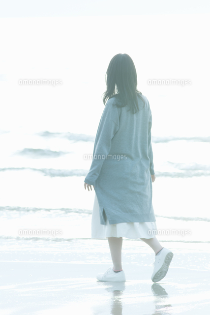 波打ち際を歩く女性の後ろ姿 の写真素材 イラスト素材 アマナイメージズ