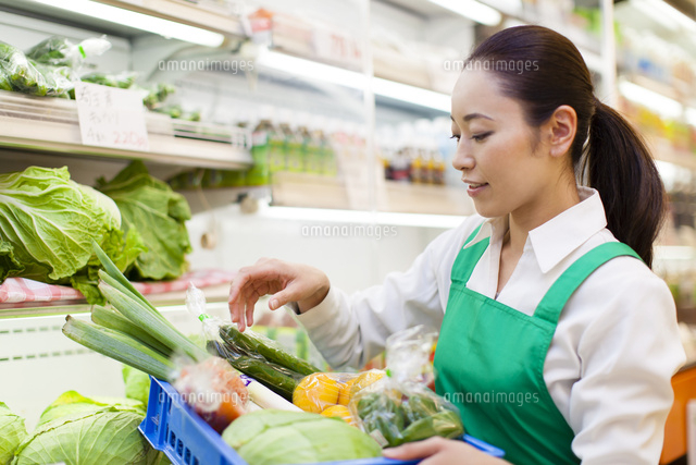 スーパーマーケットで野菜の入った箱を持つ女性店員 の写真素材 イラスト素材 アマナイメージズ