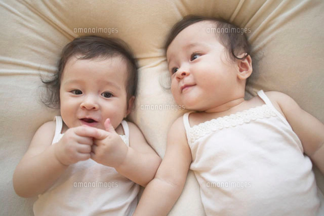 寝転ぶ双子の女の赤ちゃん[10132008655]の写真・イラスト素材｜アマナ