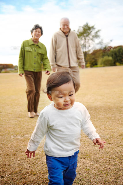 芝生の上でおじいちゃんとおばあちゃんと散歩する孫 の写真素材 イラスト素材 アマナイメージズ