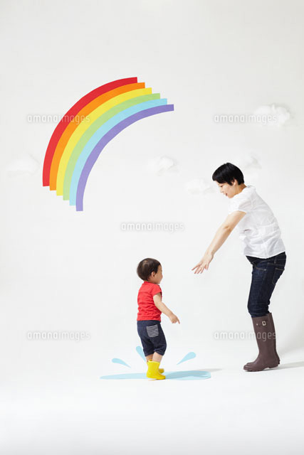 虹の下の水たまりで遊ぶお母さんと子ども の写真素材 イラスト素材 アマナイメージズ