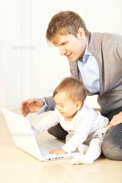 床の上でノートパソコンの画面を見る赤ちゃんと父親 の写真素材 イラスト素材 アマナイメージズ