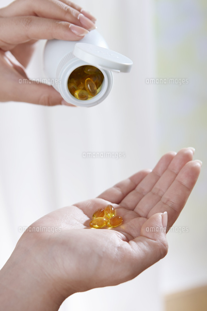 サプリメントを飲む女性の手 の写真素材 イラスト素材 アマナイメージズ