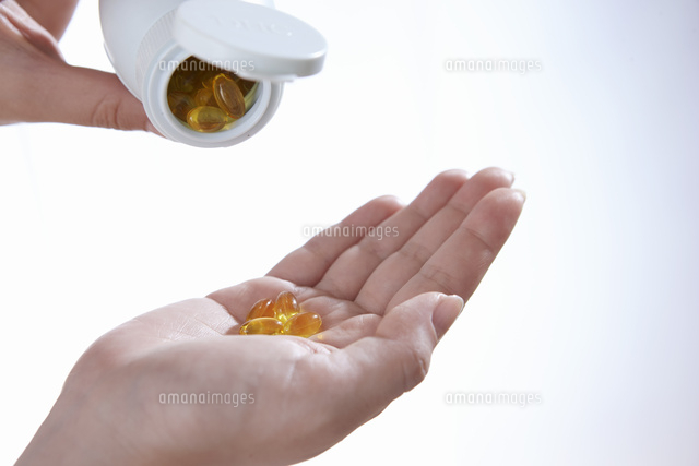サプリメントを飲む女性の手 の写真素材 イラスト素材 アマナイメージズ