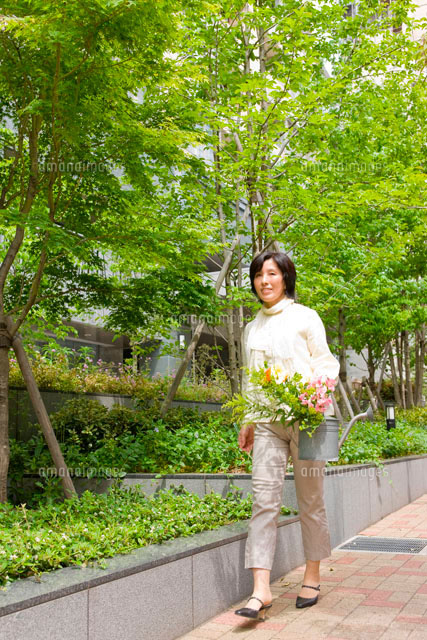 花を持って歩く中年女性[10142000393]の写真・イラスト素材｜アマナ 