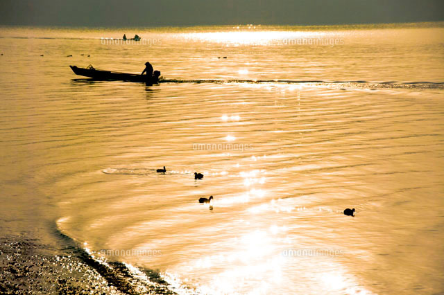 朝日に染まる穏やかな湖面と行く小舟 の写真素材 イラスト素材 アマナイメージズ