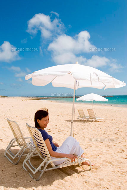 ビーチチェアに腰かけているシニア女性 の写真素材 イラスト素材 アマナイメージズ