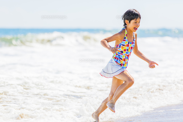 波打ち際で遊ぶ水着の女の子 の写真素材 イラスト素材 アマナイメージズ