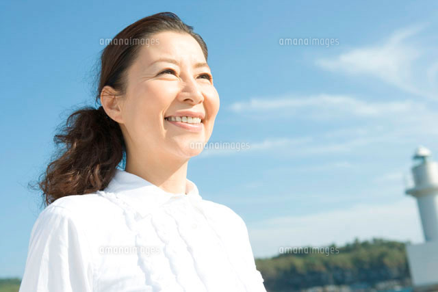 青空の下で笑う50代女性のポートレート の写真素材 イラスト素材 アマナイメージズ