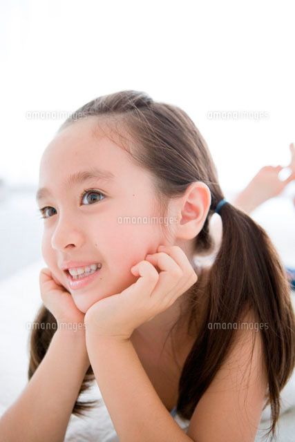 うつ伏せになり肘をつく笑顔の女の子 の写真素材 イラスト素材 アマナイメージズ