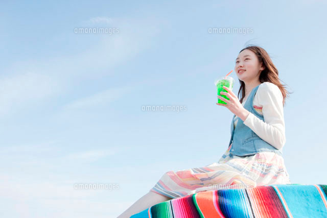青空の下でジュースを飲む10代の女の子 の写真素材 イラスト素材 アマナイメージズ