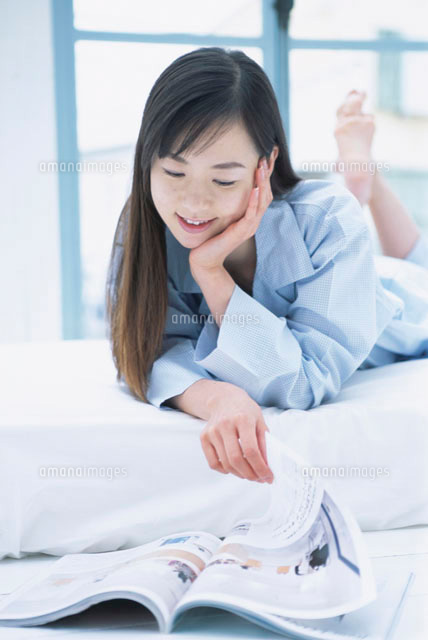 頬杖をついて雑誌を読むパジャマ姿の日本人女性 の写真素材 イラスト素材 アマナイメージズ