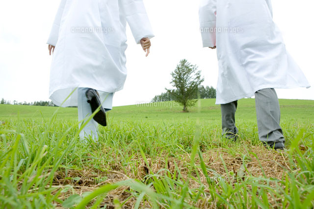白衣で草原を歩く後姿の男性と女性の足元 の写真素材 イラスト素材 アマナイメージズ