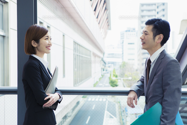 屋外で話すスーツ姿の男女 の写真素材 イラスト素材 アマナイメージズ