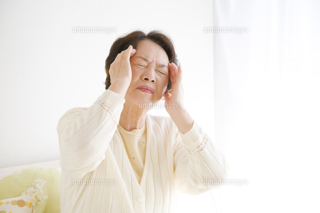 こめかみを押さえるシニア女性 の写真素材 イラスト素材 アマナイメージズ