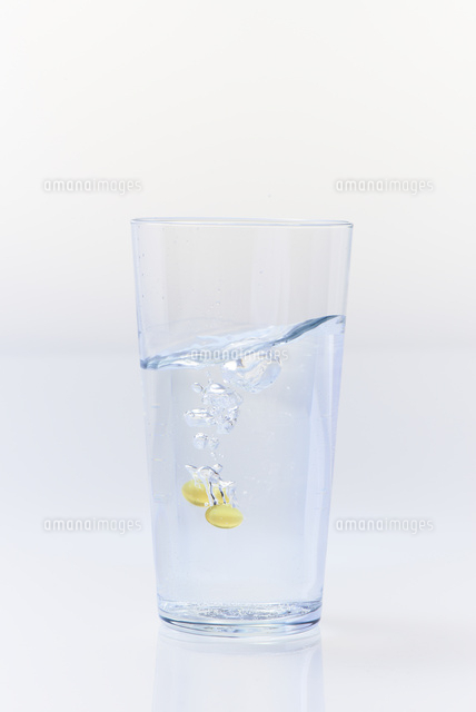 水の入ったグラスに沈んでいくビタミンカプセル の写真素材 イラスト素材 アマナイメージズ