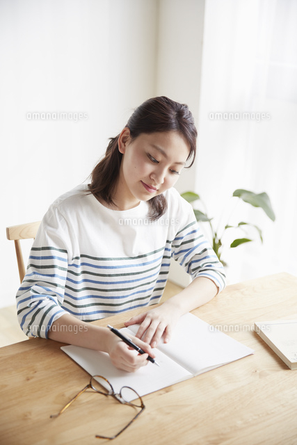 ノートに書く若い女性 の写真素材 イラスト素材 アマナイメージズ