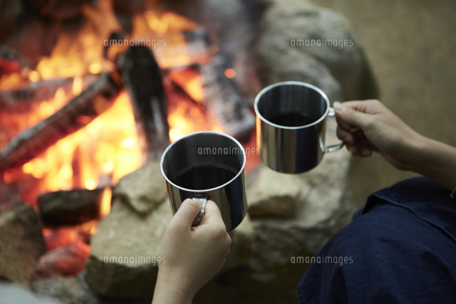 焚き火を囲ってコーヒーを飲む二人 の写真素材 イラスト素材 アマナイメージズ