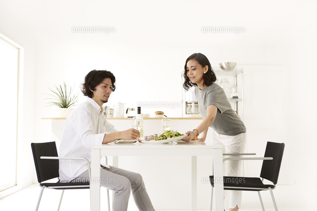 白いダイニングテーブルで食事する男女 の写真素材 イラスト素材 アマナイメージズ
