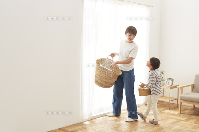 洗濯物が入ったカゴを運ぶ親子 の写真素材 イラスト素材 アマナイメージズ