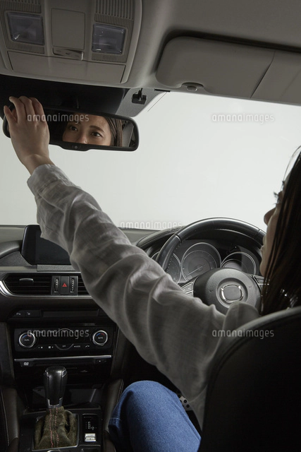 バックミラーを確認する運転席の女性[10179013780]の写真・イラスト 