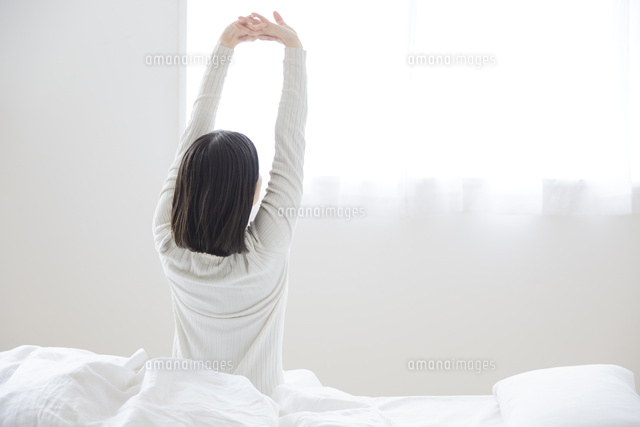 ベッドの上で伸びをする女性 の写真素材 イラスト素材 アマナイメージズ