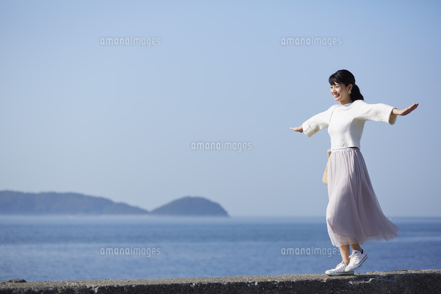 堤防の上を歩く女性 の写真素材 イラスト素材 アマナイメージズ