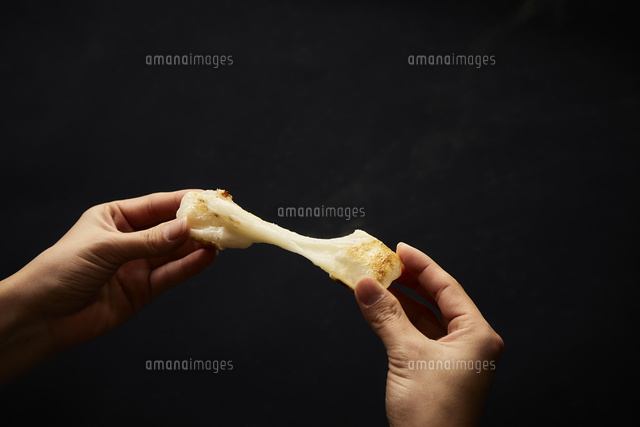 黒い背景で餅を割って伸ばしている手 の写真素材 イラスト素材 アマナイメージズ