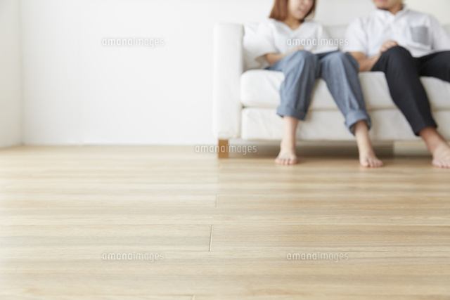 シンプルな部屋で白いソファに座って話す男女 の写真素材 イラスト素材 アマナイメージズ