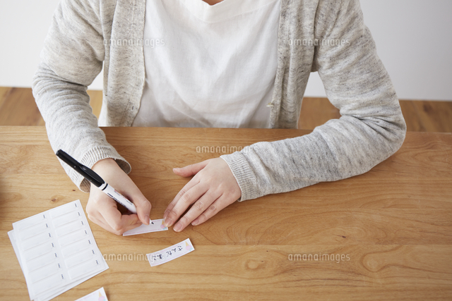ネームタグに名前を書く女性の手元 の写真素材 イラスト素材 アマナイメージズ