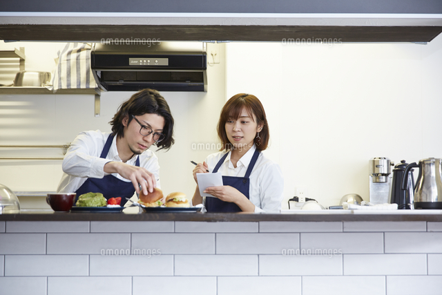 店長に教えてもらいメモを取るカフェ店員 の写真素材 イラスト素材 アマナイメージズ