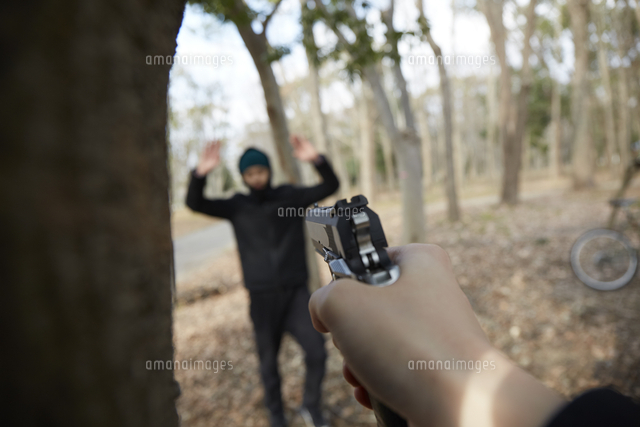 怪しい人に向かって銃を構えている手 の写真素材 イラスト素材 アマナイメージズ