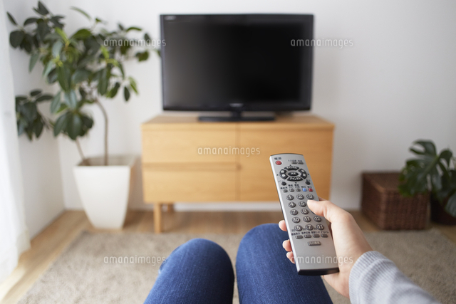 リビングのテレビをリモコンで操作する手元 の写真素材 イラスト素材 アマナイメージズ