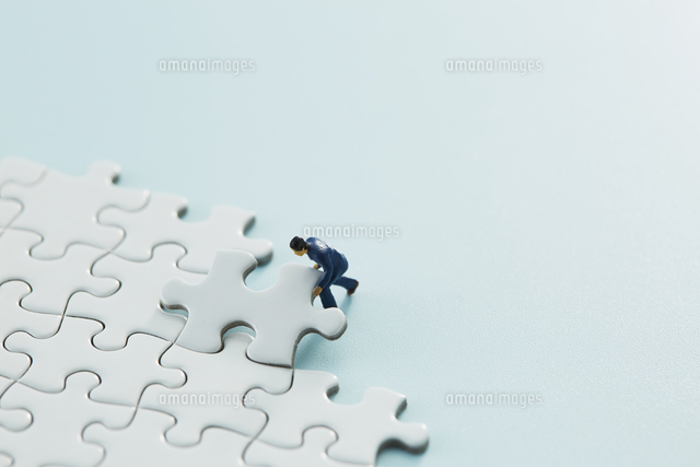 真っ白なパズルの1ピースをはめるスーツ姿のミニチュア人形 の写真素材 イラスト素材 アマナイメージズ