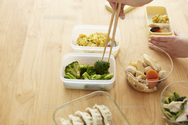 タッパーに入った食材を弁当箱に詰める女性 の写真素材 イラスト素材 アマナイメージズ