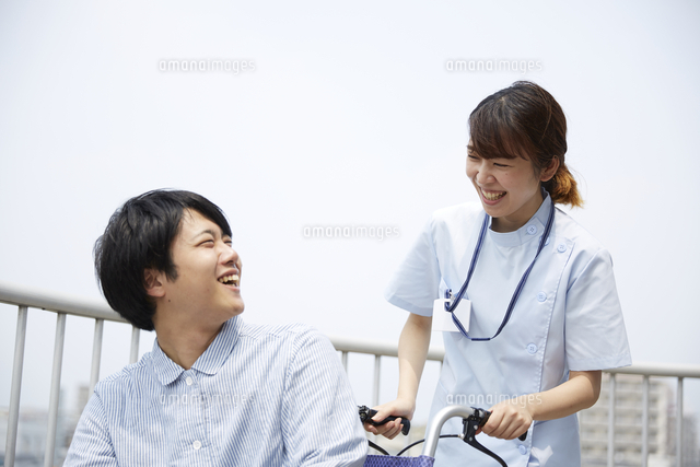 屋上で笑顔で話す車椅子の患者と女性の看護師 の写真素材 イラスト素材 アマナイメージズ