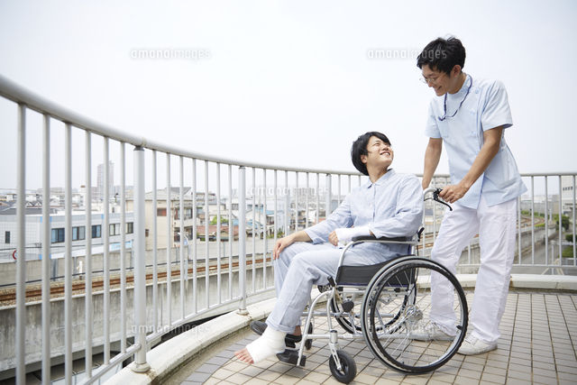 屋上で笑顔で話す車椅子の患者と男性の看護師 の写真素材 イラスト素材 アマナイメージズ