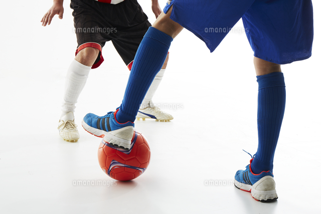 サッカーの試合でボールを蹴る人と守る人の足 の写真素材 イラスト素材 アマナイメージズ