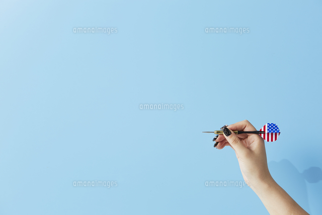 水色の背景にダーツを持った女性の手 の写真素材 イラスト素材 アマナイメージズ