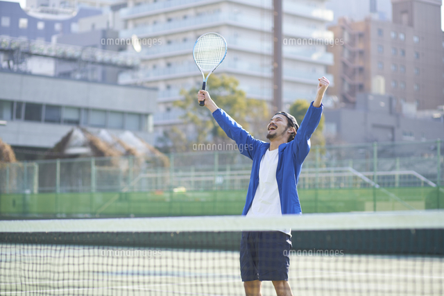 テニスコートで喜ぶ男性 の写真素材 イラスト素材 アマナイメージズ