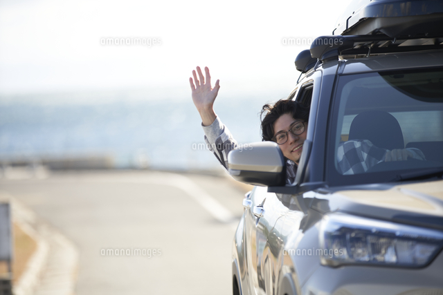 車の窓から顔を出して手を振る男性 の写真素材 イラスト素材 アマナイメージズ