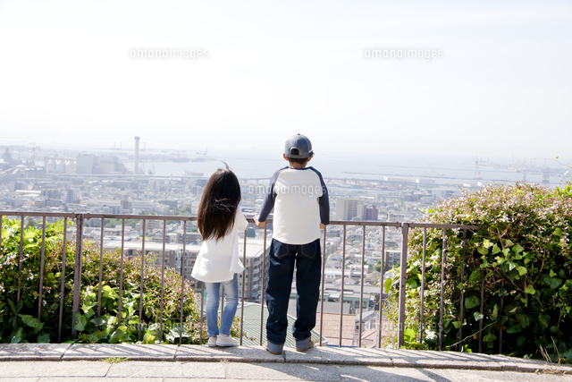 高台から街並みを眺める幼い兄妹[10186003650]の写真・イラスト素材 