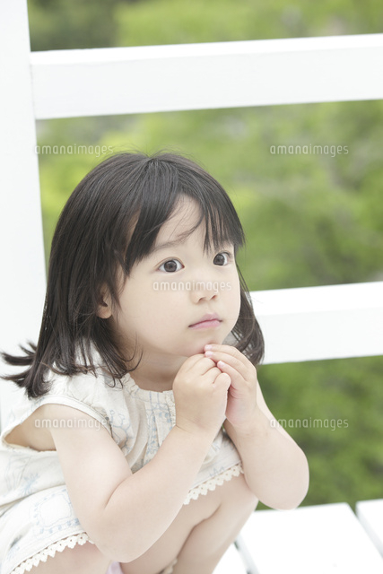 新緑を背にしゃがむ女の子 の写真素材 イラスト素材 アマナイメージズ