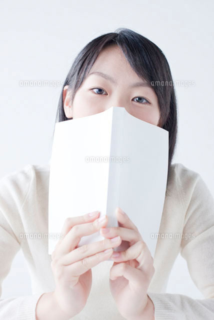 本で口を隠す女子高校生 の写真素材 イラスト素材 アマナイメージズ