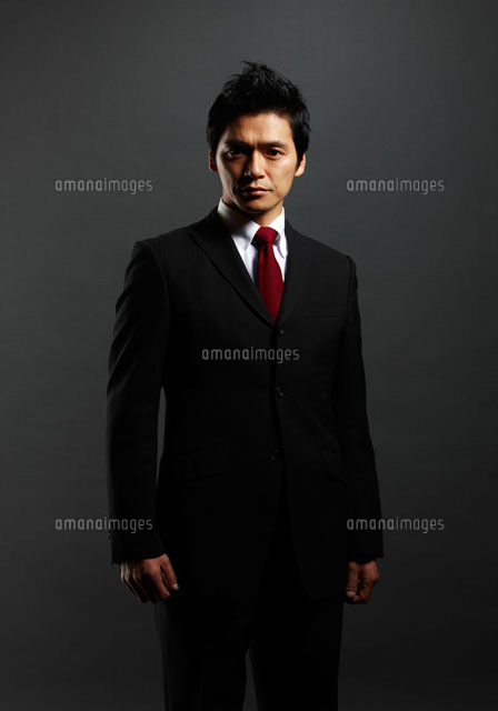 ポートレート写真 黒シャツ 黒バックの前に立つ男性ビジネスマンのポートレート[10230002286]の