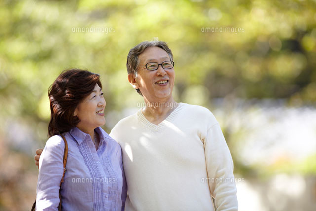 緑の中で妻の肩に手をまわすシニア男性 の写真素材 イラスト素材 アマナイメージズ