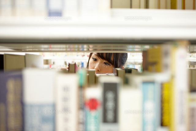 本棚越しに見える本を選んでいる女子大生の目元 の写真素材 イラスト素材 アマナイメージズ