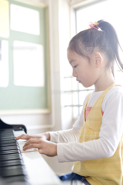 ピアノを弾いている小学生の女の子 の写真素材 イラスト素材 アマナイメージズ